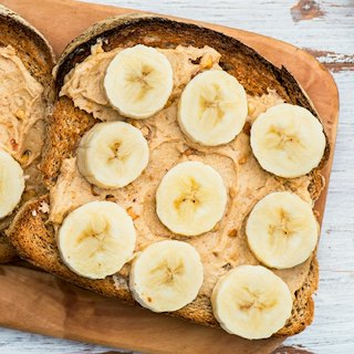 Healthy Snack Alternative made from Toasts from Wholewheat Bread with Peanut Butter and Banana with Cinnamon, Light Background